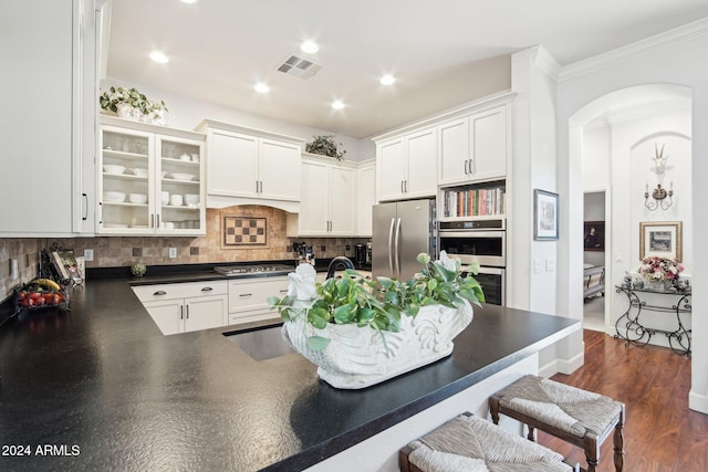 kitchen featuring white cabinets, backsplash, appliances with stainless steel finishes, and dark hardwood / wood-style floors