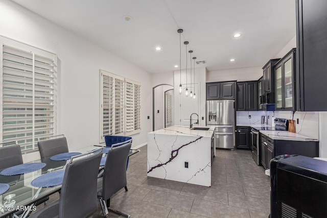 20689 W Valley View Dr, Buckeye, AZ 85396 - kitchen with appliances with stainless steel finishes, a sink, a kitchen island with sink, light stone countertops, and tile patterned flooring