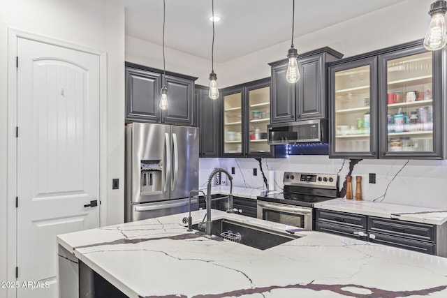 20689 W Valley View Dr, Buckeye, AZ 85396 - kitchen with appliances with stainless steel finishes, a sink, glass insert cabinets, pendant lighting, and light stone countertops