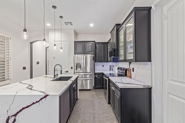20689 W Valley View Dr, Buckeye, AZ 85396 - kitchen featuring stainless steel appliances, a sink, light stone counters, decorative light fixtures, and light tile patterned floors