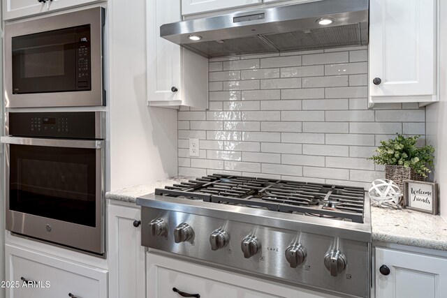 6397 E Red Oak Cir, Hereford, AZ 85615 - kitchen with decorative backsplash, light stone countertops, under cabinet range hood, stainless steel appliances, and white cabinetry