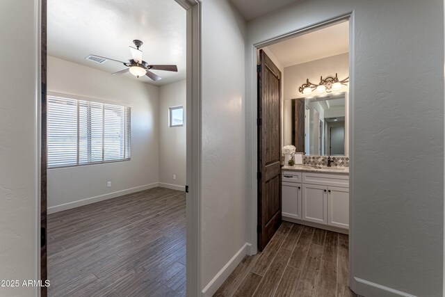 6397 E Red Oak Cir, Hereford, AZ 85615 - corridor featuring visible vents, a textured wall, baseboards, a sink, and dark wood finished floors