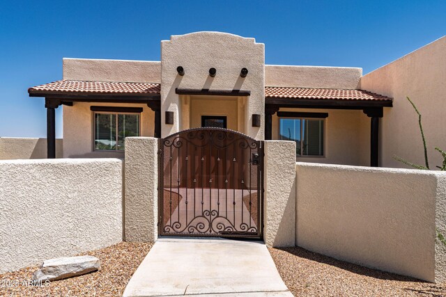 6397 E Red Oak Cir, Hereford, AZ 85615 - pueblo-style home featuring a tiled roof, a gate, a fenced front yard, and stucco siding