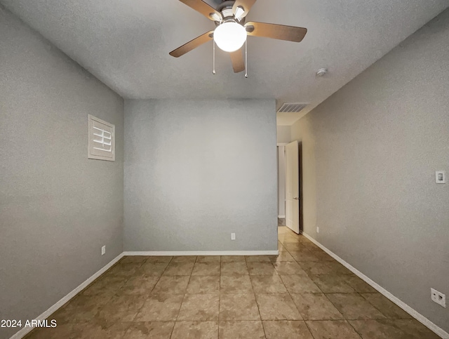 tiled empty room featuring a textured ceiling and ceiling fan