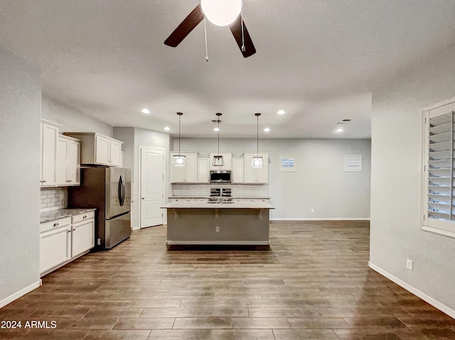 kitchen with appliances with stainless steel finishes, dark hardwood / wood-style flooring, a kitchen island with sink, ceiling fan, and decorative light fixtures