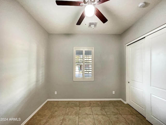 unfurnished bedroom with tile patterned flooring, a closet, and ceiling fan