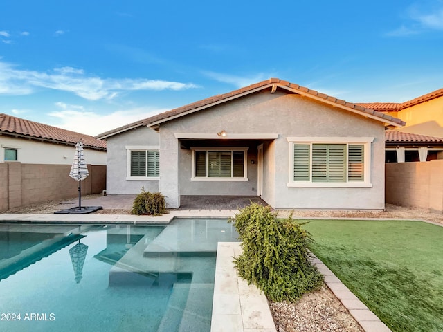 rear view of property with a fenced in pool