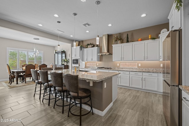 5250 S Wesley Cir, Mesa, AZ 85212 - kitchen with wall chimney range hood, stainless steel appliances, white cabinets, a kitchen bar, and recessed lighting