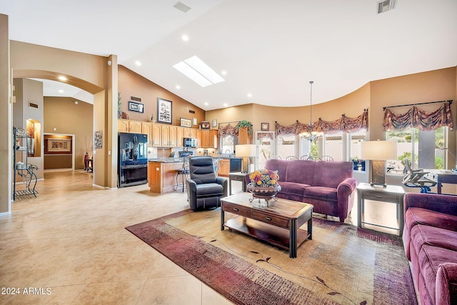 living room featuring high vaulted ceiling, a chandelier, a skylight, and light tile patterned floors