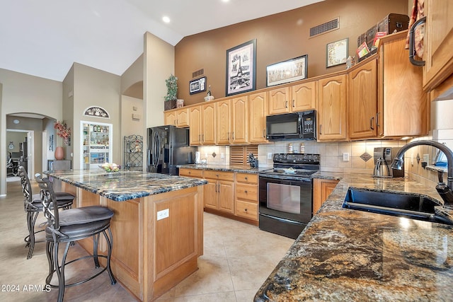 kitchen featuring dark stone counters, sink, a kitchen island, high vaulted ceiling, and black appliances