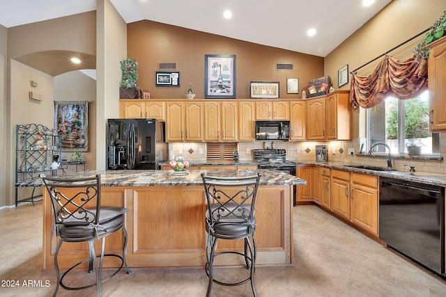 kitchen with a kitchen island, backsplash, black appliances, a breakfast bar area, and dark stone counters