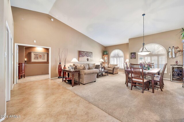 tiled living room featuring a notable chandelier, a skylight, and high vaulted ceiling