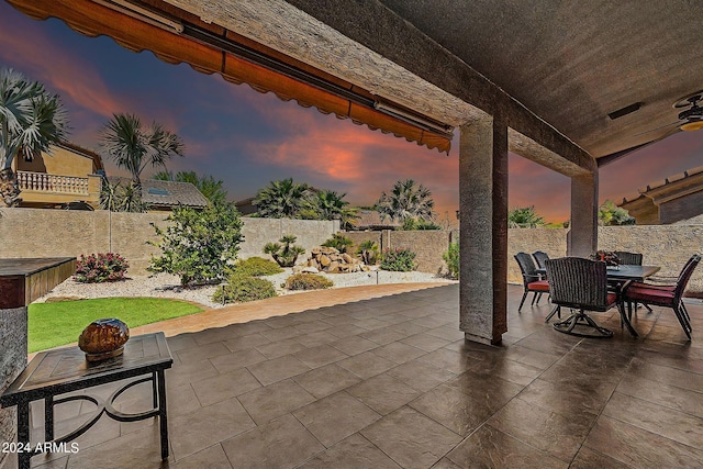 patio terrace at dusk featuring a yard