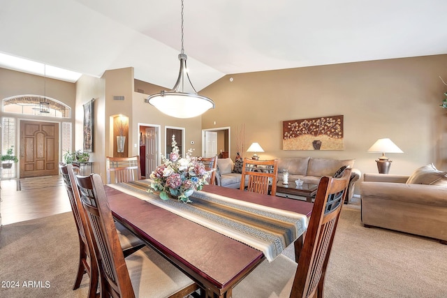 carpeted dining area featuring high vaulted ceiling