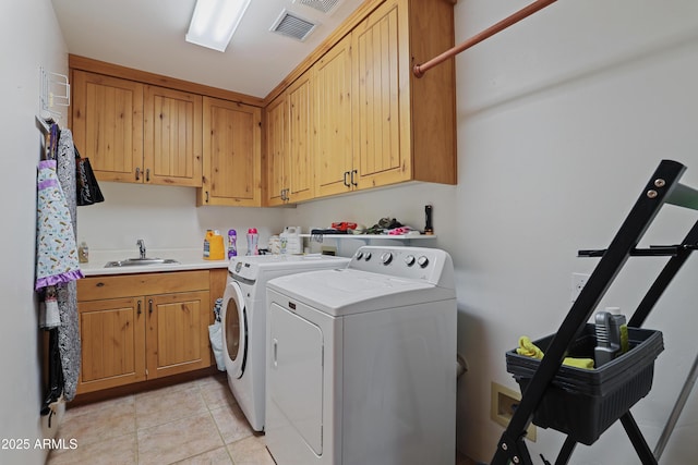 clothes washing area featuring separate washer and dryer, sink, light tile patterned flooring, and cabinets