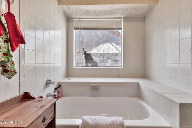 full bath featuring a garden tub and a textured ceiling