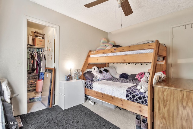 carpeted bedroom with a ceiling fan, a textured ceiling, a closet, and a spacious closet