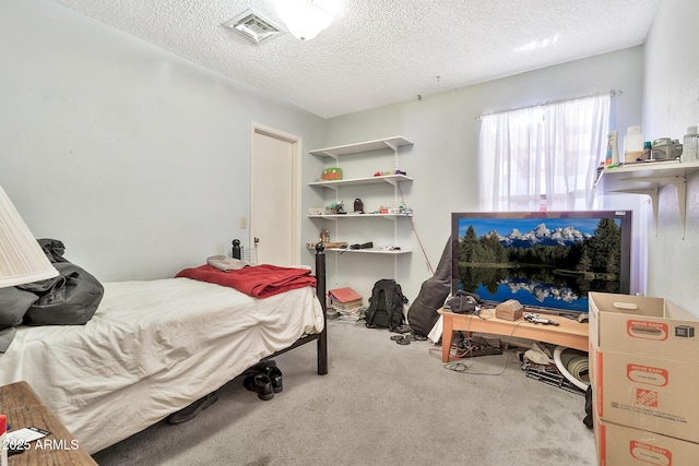 bedroom featuring visible vents, a textured ceiling, and carpet