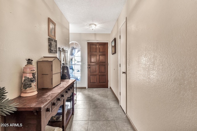 foyer entrance featuring light tile patterned floors, a textured ceiling, and a textured wall