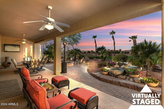 patio terrace at dusk featuring ceiling fan and an outdoor hangout area