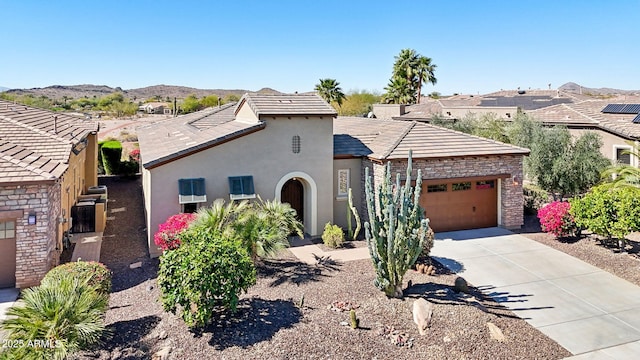 view of front of house with stucco siding, an attached garage, a mountain view, stone siding, and driveway