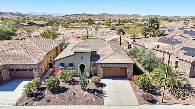 view of front of property featuring concrete driveway, stone siding, an attached garage, a mountain view, and stucco siding