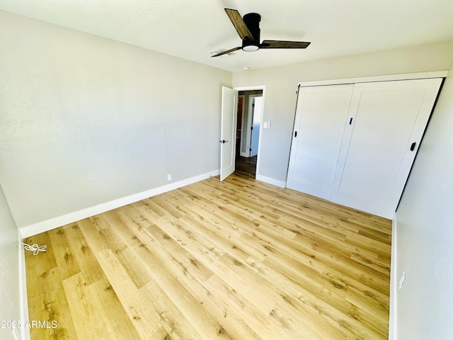 unfurnished bedroom with a closet, a ceiling fan, light wood-type flooring, and baseboards