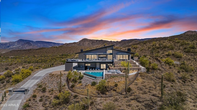 back house at dusk featuring a mountain view and a patio area