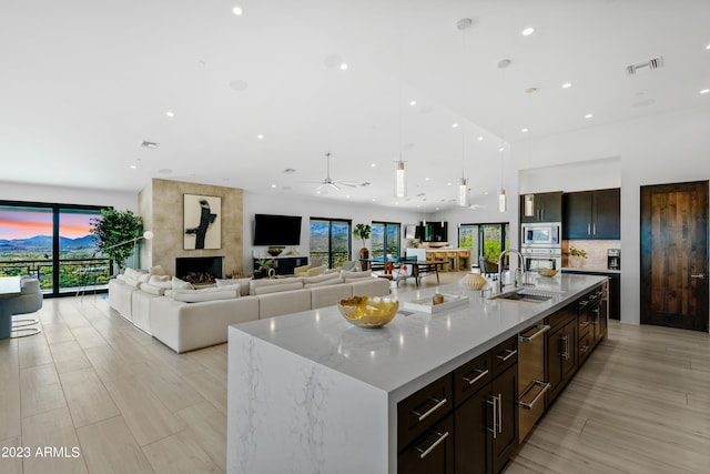 kitchen featuring hanging light fixtures, appliances with stainless steel finishes, sink, and a center island with sink