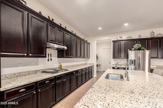 kitchen with light stone countertops, dark brown cabinetry, appliances with stainless steel finishes, sink, and light tile patterned flooring