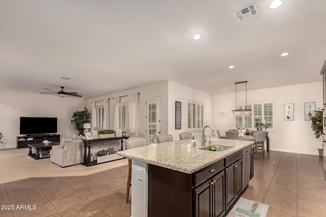 kitchen featuring pendant lighting, sink, ceiling fan, a breakfast bar, and dark brown cabinets