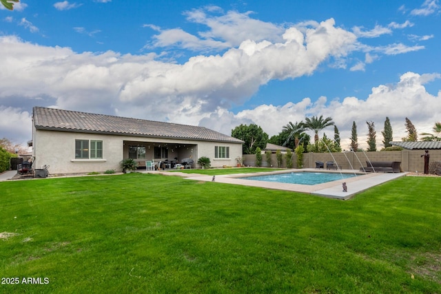 back of property featuring a fenced in pool, a yard, pool water feature, and a patio