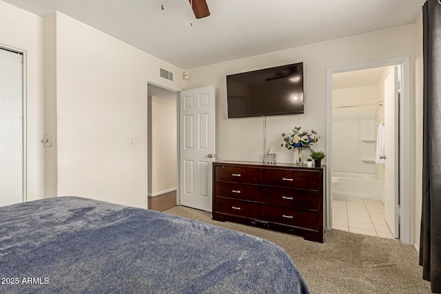 bedroom with visible vents, a ceiling fan, connected bathroom, tile patterned floors, and carpet flooring