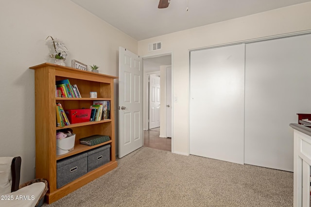 sitting room with carpet floors, visible vents, and a ceiling fan