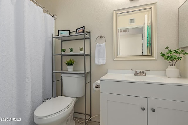 bathroom with toilet, vanity, and visible vents