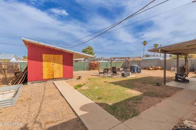 view of yard with a storage shed, an outdoor fire pit, a patio, a fenced backyard, and an outdoor structure