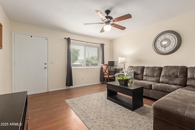 living room featuring baseboards, a ceiling fan, and wood finished floors