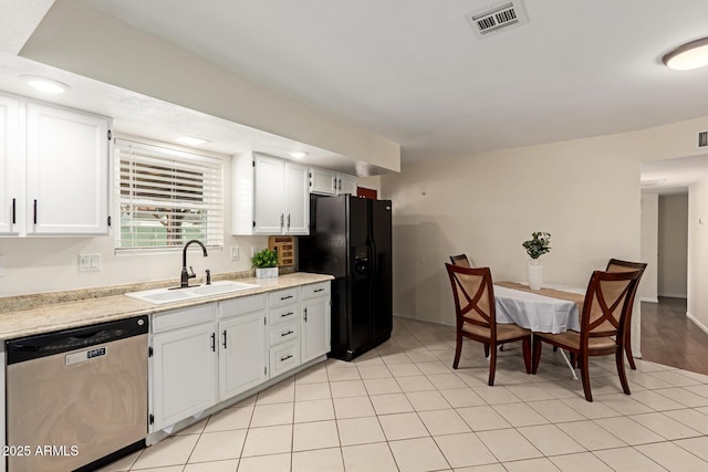 kitchen with visible vents, light countertops, black fridge, stainless steel dishwasher, and a sink