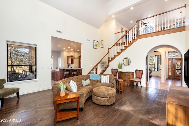 living room featuring a healthy amount of sunlight, dark hardwood / wood-style flooring, and a towering ceiling