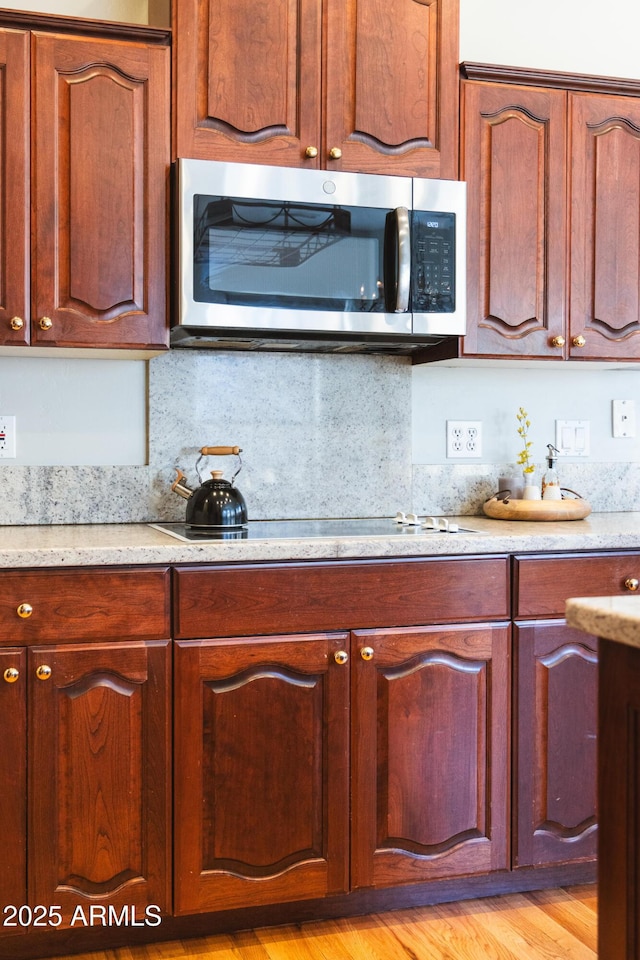 kitchen featuring stovetop, decorative backsplash, and light hardwood / wood-style flooring