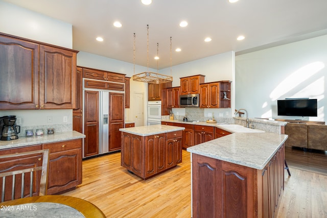 kitchen with sink, paneled built in fridge, light hardwood / wood-style floors, and a kitchen island