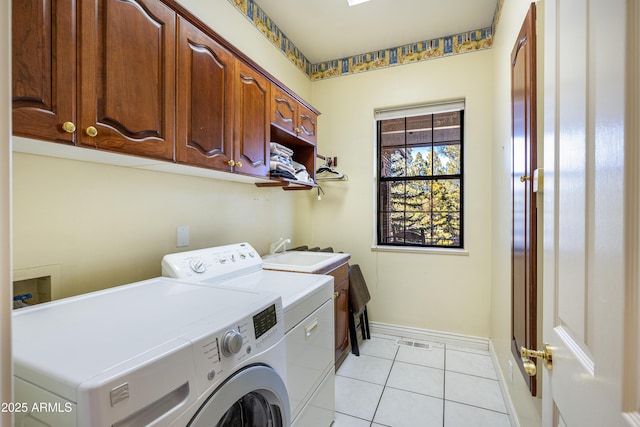 washroom with cabinets, washing machine and clothes dryer, sink, and light tile patterned floors