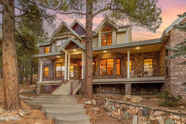 back house at dusk featuring a porch