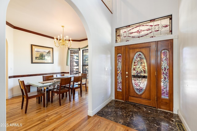 foyer with crown molding and a notable chandelier