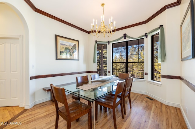 dining area with an inviting chandelier, light hardwood / wood-style flooring, ornamental molding, and a healthy amount of sunlight