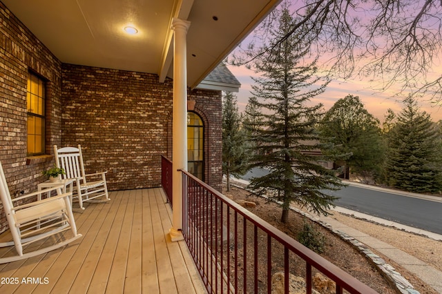 balcony at dusk featuring a porch