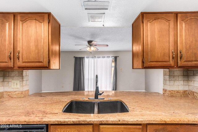 kitchen with backsplash, a textured ceiling, ceiling fan, sink, and dishwasher