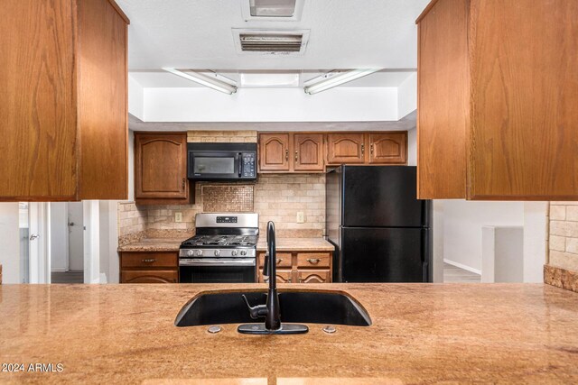 kitchen with black appliances, decorative backsplash, and sink