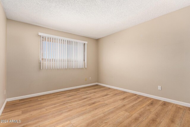 unfurnished room featuring light hardwood / wood-style floors and a textured ceiling