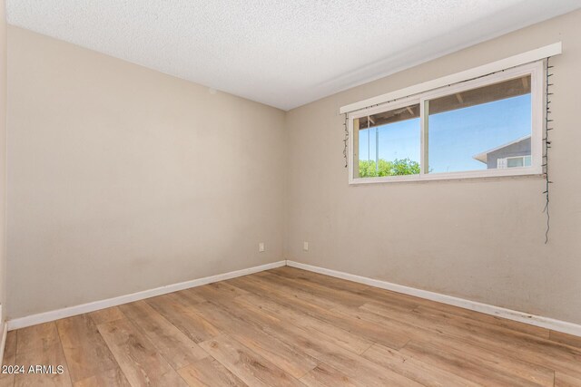 unfurnished room with a textured ceiling and light hardwood / wood-style flooring